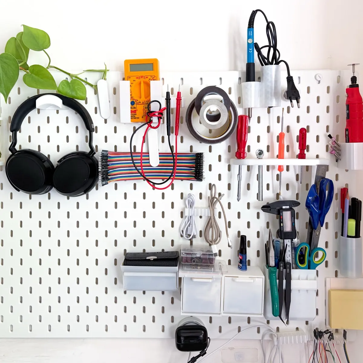 White 3D-printed Skadis attachments organizing tools on a pegboard.
