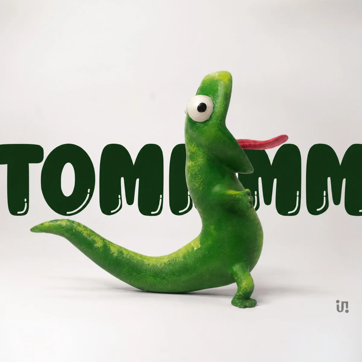 Tommm, a bright-green hand-painted lizard balanced on its tail.